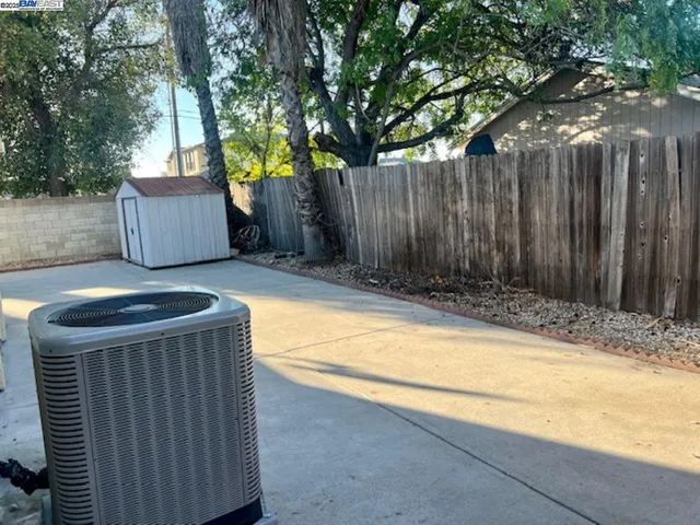 a backyard of a house with large trees and wooden fence