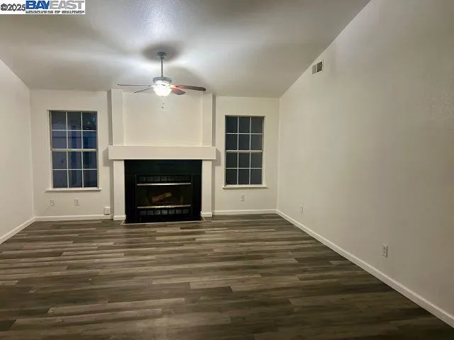 an empty room with wooden floor fireplace and window
