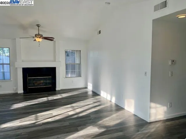 a view of an empty room with wooden floor fireplace and a window