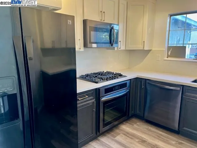 a kitchen with stainless steel appliances granite countertop a refrigerator and a stove top oven