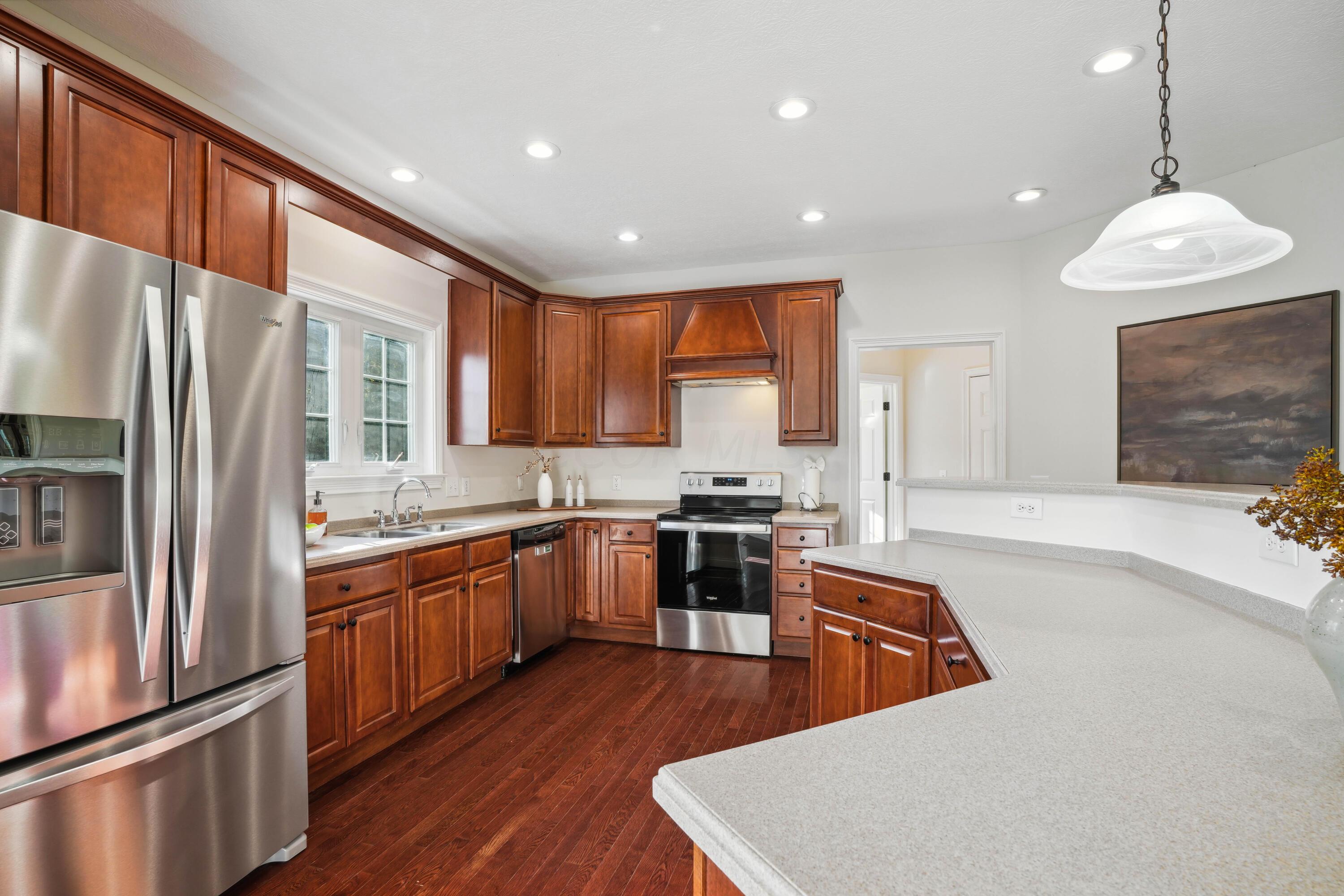 10403 Liberty Road Powell, OH 43065 - Photo 21 of 76 Open Kitchen with countertop seating, NEW SS appliances, Dining Area, Cherry cabinets with custom vent hood, corian countertops and walk-in pantry plus beautiful hardwood floors!