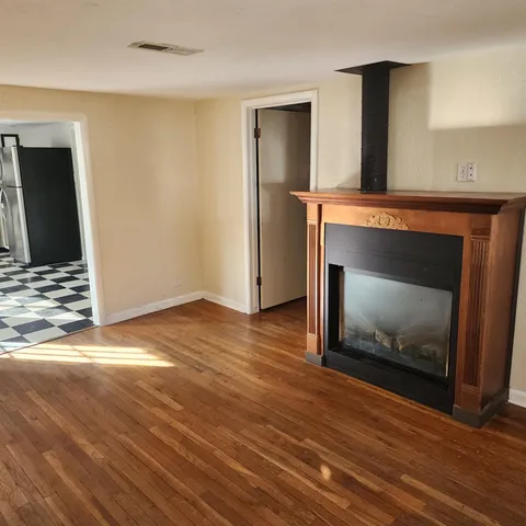 a view of an empty room with wooden floor and a fireplace
