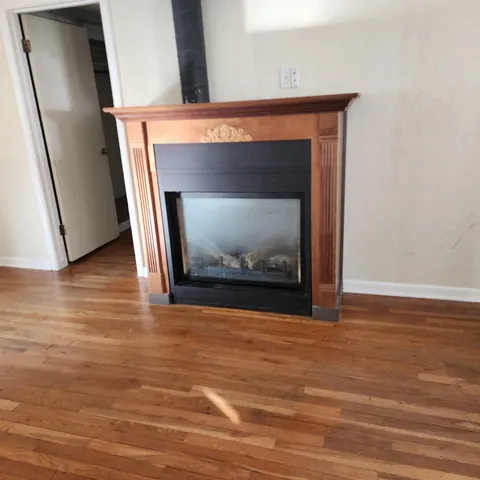 a view of an empty room with wooden floor and a fireplace