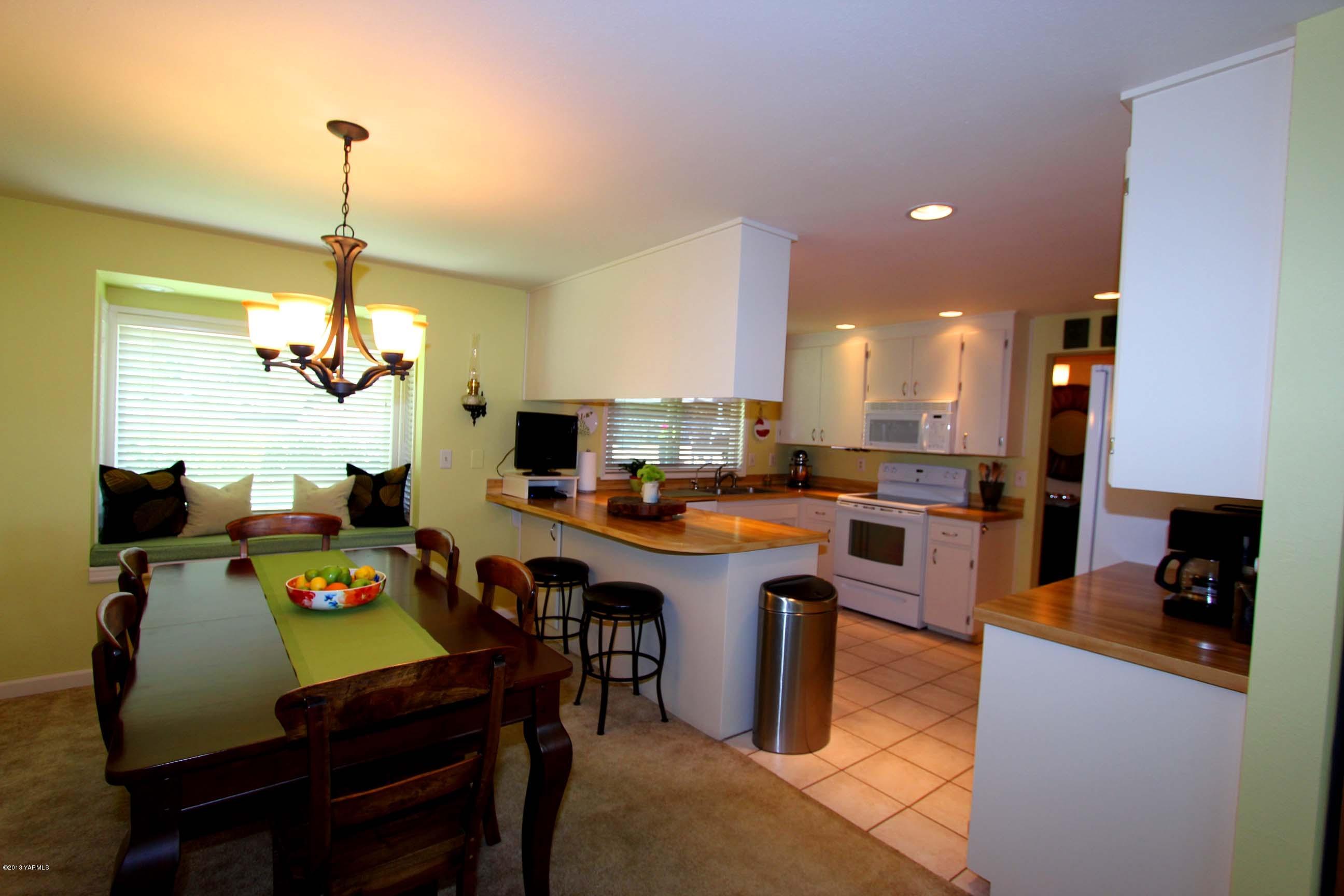 170 Wilcox Road Cowiche, WA 98923 - Photo 10 of 39 a kitchen island with stainless steel appliances a stove a sink a dining table and chairs with wooden floor