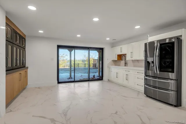 a large white kitchen with stainless steel appliances granite countertop a stove and a refrigerator