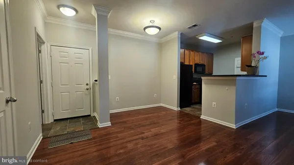 an empty room with wooden floor and a kitchen