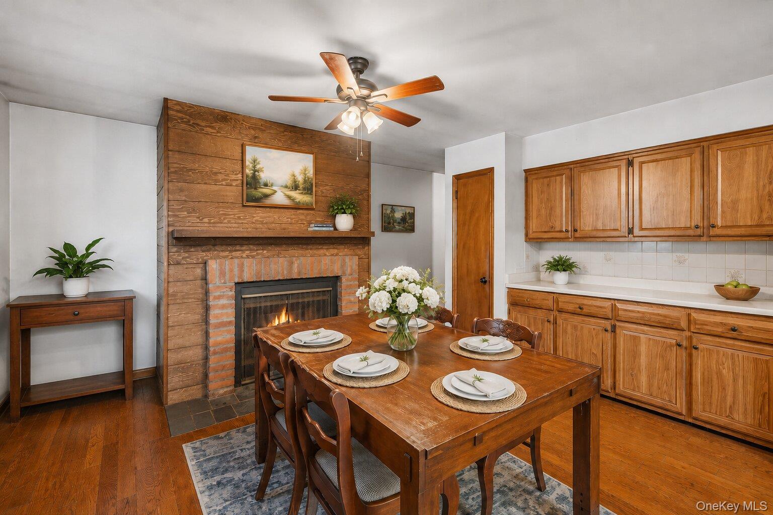 49 Chase Road Wallkill, NY 12589 - Photo 8 of 32 Virtually Staged Dining Area: Warm and inviting formal dining room featuring hardwood floors, a brick fireplace, wood accent details, and plenty of room for gatherings.