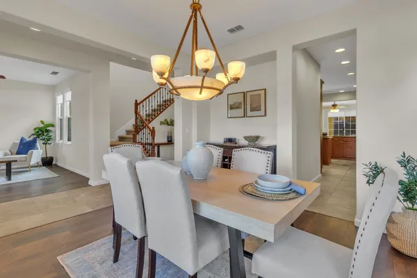 a view of staircase with lots of frames on wall and a dining table