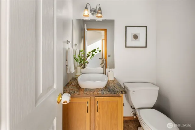 a bathroom with a granite countertop toilet sink and mirror