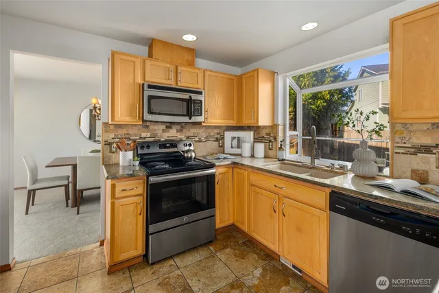 a kitchen with stainless steel appliances granite countertop a stove a sink and a microwave