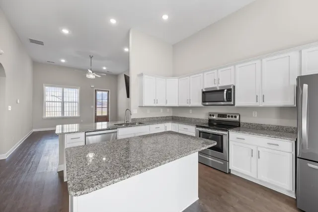 a kitchen with stainless steel appliances granite countertop a sink stove and microwave