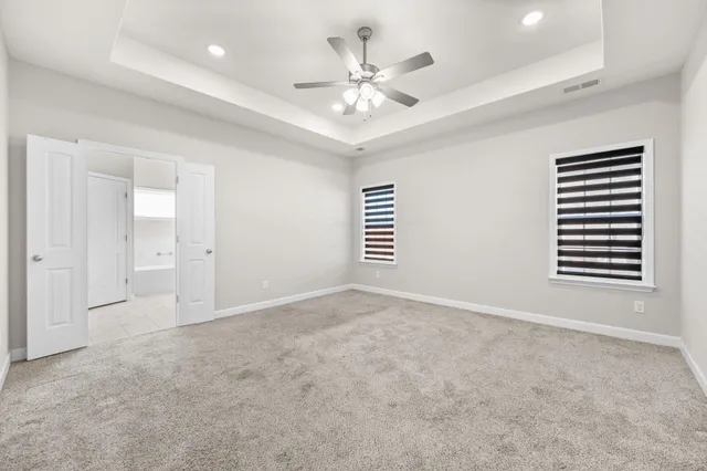 an empty room with windows and ceiling fan