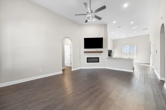 a view of a livingroom with a flat screen tv wooden floor and a ceiling fan