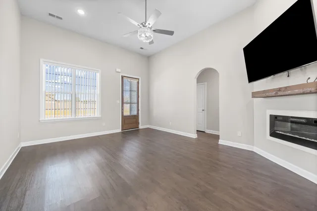 an empty room with windows fireplace and wooden floor