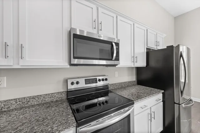 a kitchen with stainless steel appliances granite countertop a refrigerator stove and microwave