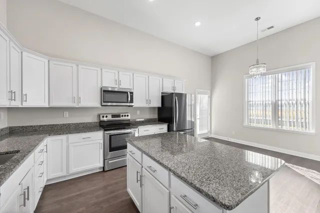a kitchen with granite countertop a sink stainless steel appliances and white cabinets