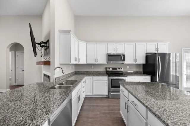 a kitchen with stainless steel appliances granite countertop a sink stove and refrigerator