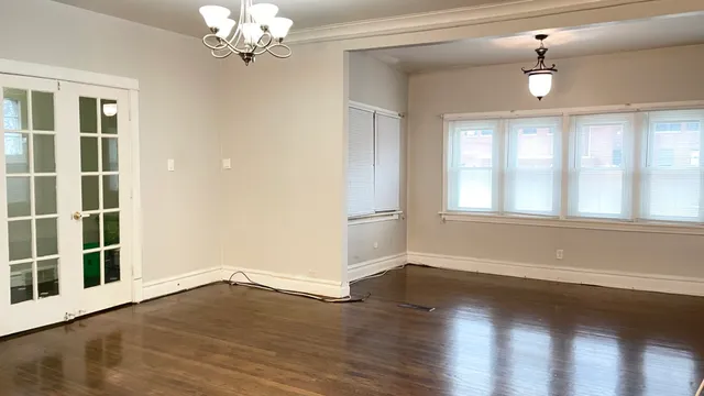 a view of an empty room with a window and wooden floor