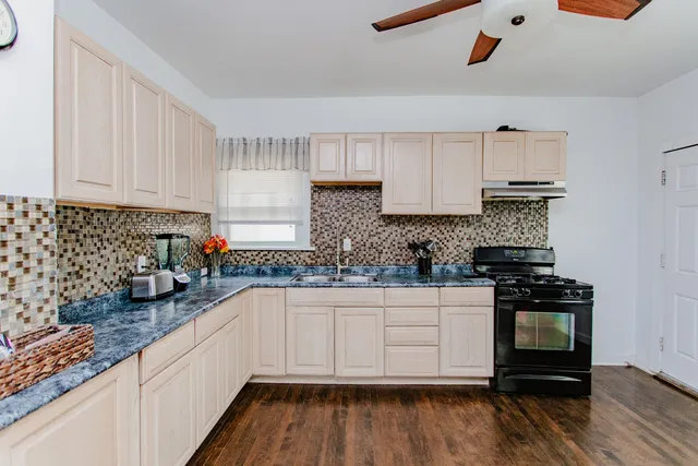 a kitchen with granite countertop a sink a stove and cabinets