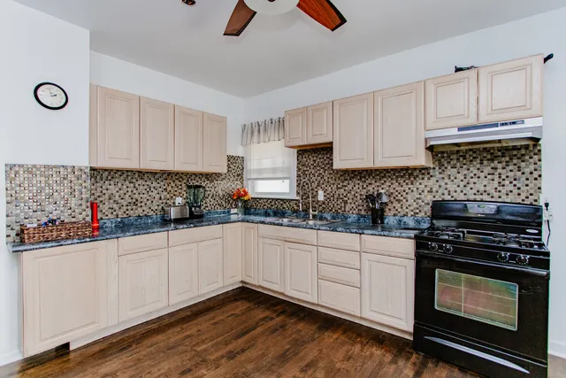a kitchen with stainless steel appliances granite countertop a table chairs and a refrigerator