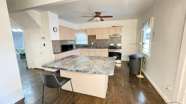 a kitchen with kitchen island a counter top space a sink stainless steel appliances and cabinets