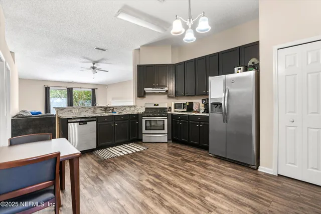 a kitchen with a chandelier a sink stainless steel appliances and cabinets