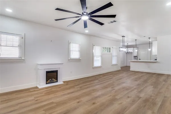 a view of empty room with kitchen and fireplace
