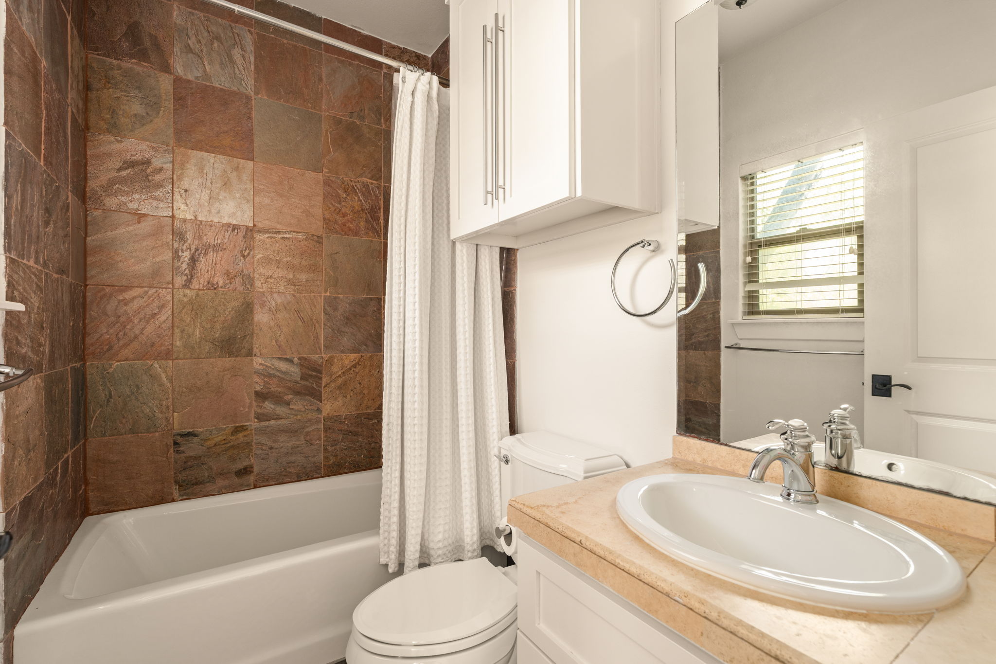 2324 Kinney Road Austin, TX 78704 - Photo 23 of 35 Rich stone wall tiling frames the tub shower in this well-appointed bathroom.