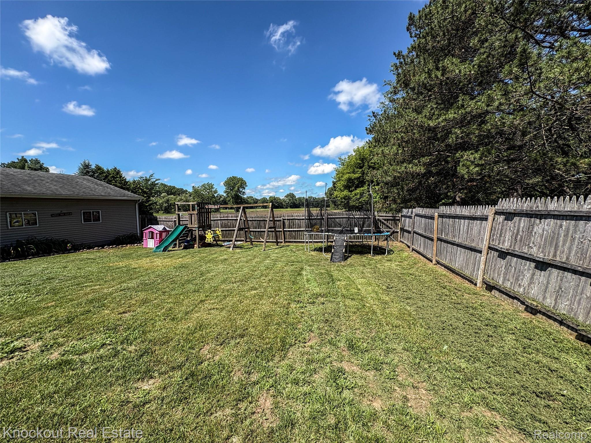 7760 Bell Road Birch Run, MI 48415 - Photo 59 of 68 Expansive backyard featuring a manicured lawn, a full-height wooden privacy fence, mature trees, and a detached structure with siding and multiple windows