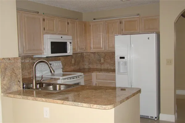 a kitchen with stainless steel appliances granite countertop a sink a stove and a refrigerator