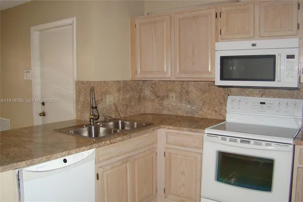 a kitchen with granite countertop white cabinets stainless steel appliances and sink