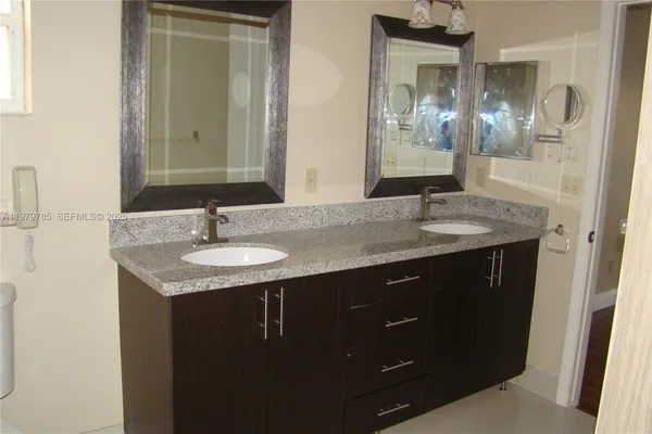 a bathroom with a granite countertop sink and a mirror