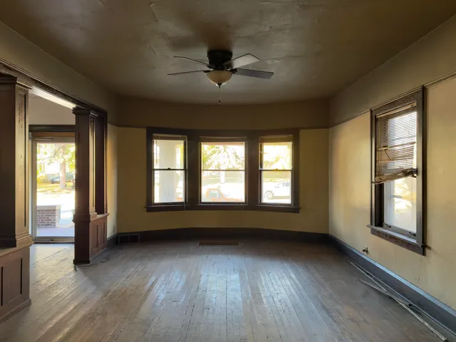 a view of an empty room with wooden floor and a window