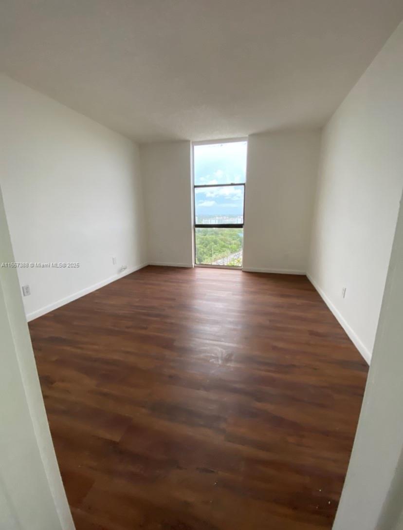 13499 Biscayne Boulevard, Unit 1507 North Miami, FL 33181 - Photo 19 of 32 a view of an empty room with a window and wooden floor