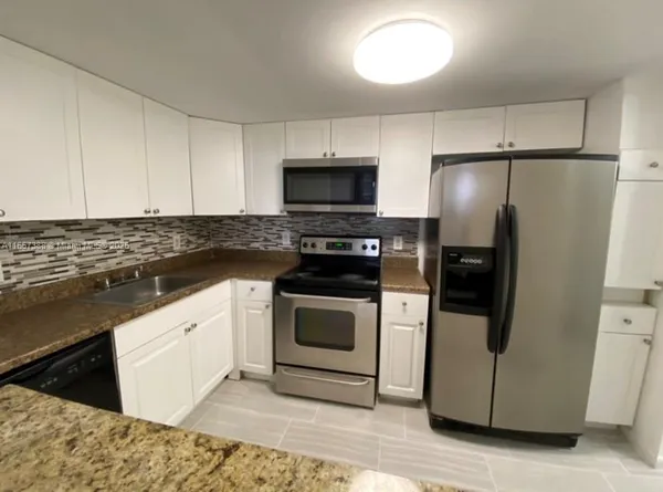a kitchen with granite countertop white cabinets and stainless steel appliances