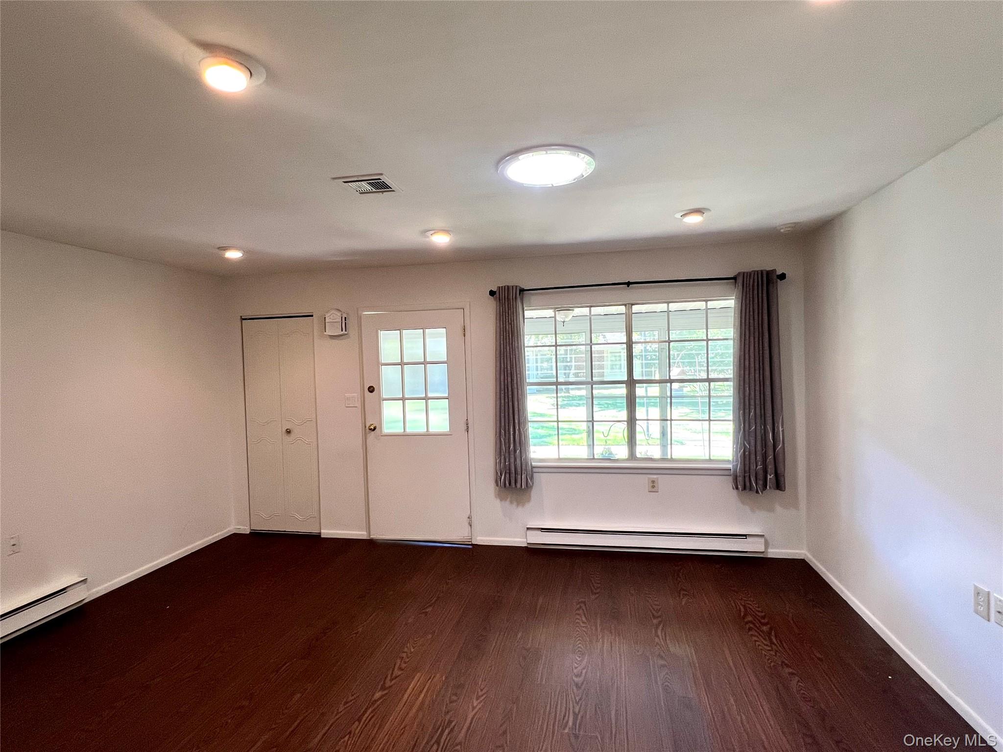 171 B Ventry Court, Unit 171B Ridge, NY 11961 - Photo 11 of 19 a view of an empty room with wooden floor and a window