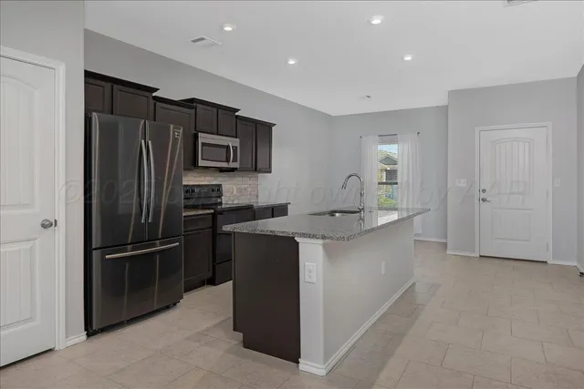 a large kitchen with a refrigerator and a sink
