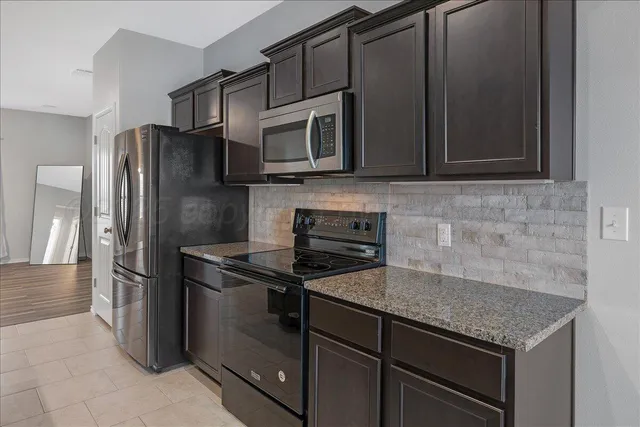 a kitchen with stainless steel appliances granite countertop a stove microwave and refrigerator