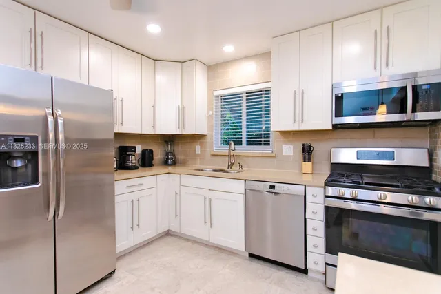 a kitchen with stainless steel appliances granite countertop a sink and white cabinets