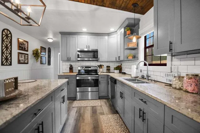 a kitchen with stainless steel appliances granite countertop a sink a stove a microwave a dining table and chairs