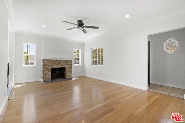 a view of empty room with wooden floor and fan
