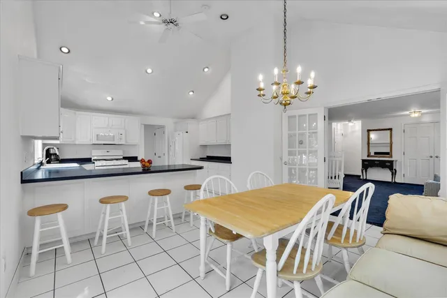a dining room filled chandelier and kitchen view