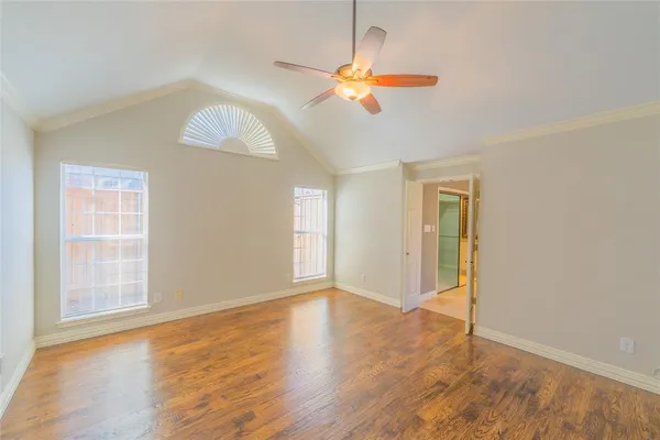 an empty room with wooden floor chandelier fan and windows