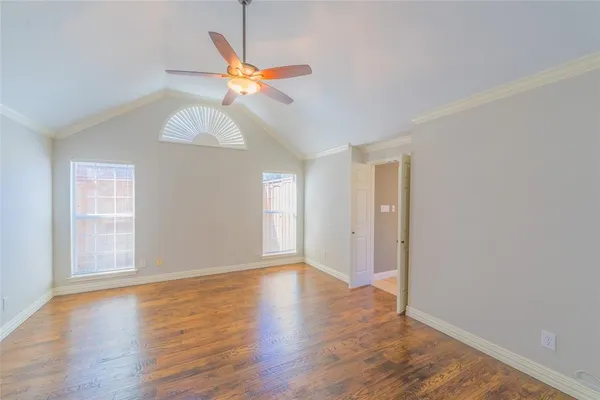 an empty room with wooden floor fan and windows