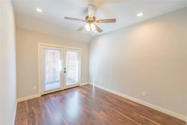 an empty room with wooden floor fan and windows