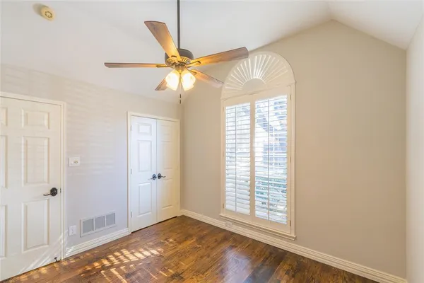a view of an empty room with window and a chandelier fan