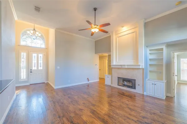 an empty room with wooden floor fireplace and windows