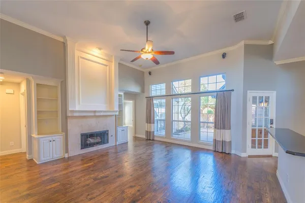 a view of an empty room with window and wooden floor
