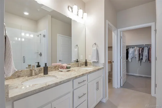 a bathroom with a granite countertop double vanity sink mirror and shower