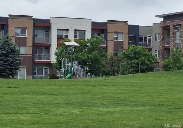 a tall building with a big yard and large trees